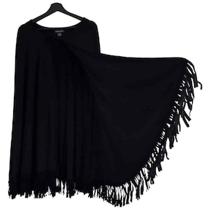 May include: A white ceramic mug with a black handle and the text "But First, Coffee" in a bold, black font. The mug is set against a blurred background. The mug appears to be approximately 10 cm tall.