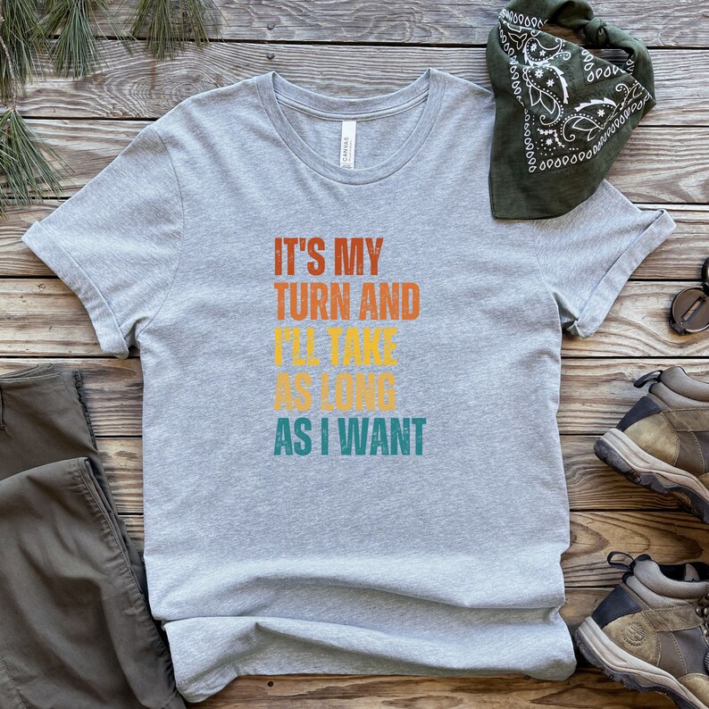 K&ouml;nnte beinhalten: Graues T-Shirt mit dem Text "It's my turn and I'll take as long as I want" in einer Vintage-Schriftart mit orange, gelb und t&uuml;rkis.