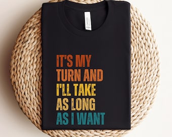 May include: Black t-shirt with a vintage-style graphic that reads "It's my turn and I'll take as long as I want."