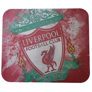 May include: A red and green Liverpool Football Club mousepad with a white crest featuring a Liver bird and the text "You'll Never Walk Alone" and "EST. 1892".