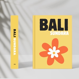Könnte beinhalten: Ein gelbes Buch mit dem Titel "BALI SUNDARA" in Schwarz und Weiß. Das Cover zeigt eine große orangefarbene und weiße Blume. Ein passender gelber Buchrücken zeigt den Titel vertikal.