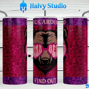 May include: A 20 ounce stainless steel tumbler with a pink glitter design. The tumbler features a graphic of a brown bear wearing pink heart-shaped sunglasses with the text "F**k Around Find Out".
