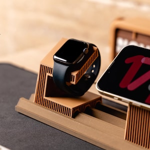Könnte beinhalten: Eine beige, 3D-gedruckte Ladestation mit gerippter Textur, die für eine schwarze Smartwatch und ein Smartphone ausgelegt ist. Der Ständer verfügt über eine gestufte Struktur mit speziellen Steckplätzen für die Geräte und ein funktionales Design.