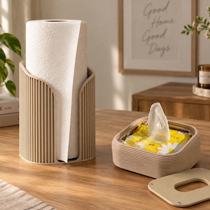 Pode incluir: Um suporte vertical bege para papel toalha com design exterior canelado contendo um rolo de papel branco, ao lado de uma caixa de lenços quadrada bege a condizer com tampa removível com uma abertura retangular central para dispensar.