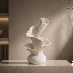 May include: A matte white ceramic vase featuring a sculptural design with three distinct, upward-curving, petal-like layers that spiral toward the top. The surface of the vase has a fine, vertical ribbed texture throughout its entire structure.