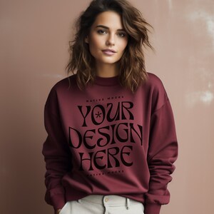 May include: A maroon sweatshirt with the text "YOUR DESIGN HERE" in black lettering. The text is in a stylized font with a star in the middle of the word "YOUR".