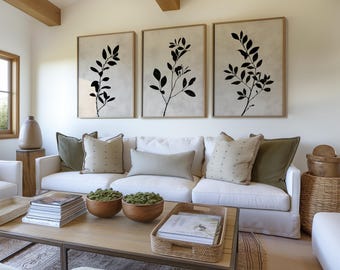 Könnte beinhalten: Ein weißes Sofa mit grünen und beigen Kissen steht in einem Wohnzimmer mit einem Couchtisch und drei Schwarz-Weiß- botanischen Drucken an der Wand.