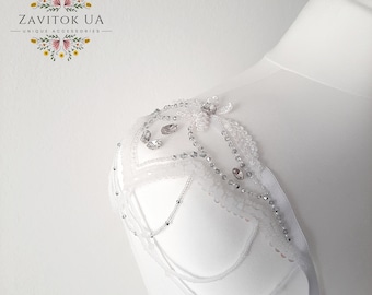 May include: White beaded shoulder piece with a floral design and clear rhinestones. The piece is attached to a white ribbon.