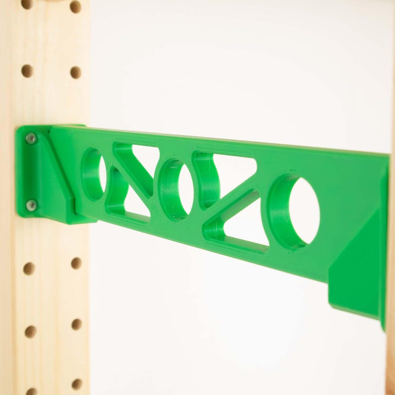 May include: A bright green shelf bracket with a geometric design, mounted on a wooden support. The bracket features circular and triangular cutouts, and is secured with screws. The design is modern and functional.