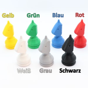 May include: A collection of colorful knight chess pieces in yellow, green, blue, and red, with white, gray, and black pieces. The German words for the colors are displayed above each piece. The pieces are arranged on a white background.