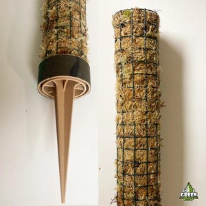 Puede incluir: Una estaca de plástico marrón con un cilindro de malla de alambre verde lleno de musgo seco. El musgo es de color marrón claro y la malla de alambre es de color verde oscuro. La estaca está diseñada para ser insertada en el suelo para mantener el cilindro de musgo en su lugar.