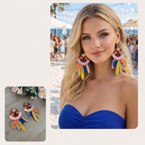 Könnte beinhalten: Bunte Statement-Ohrringe mit geometrischen Formen in Rosa, Gelb, Blau und Braun. Die Ohrringe haben goldene Haken. Das Bild zeigt die Ohrringe an einer Person mit blonden Haaren und einem blauen Oberteil.