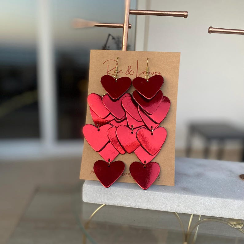 Shiny red leather heart dangle earrings crafted in multiple layers for a unique and lightweight statement look.