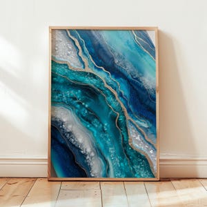 May include: Abstract art print in a wooden frame. The artwork features flowing layers of teal, blue, and white, accented with gold metallic lines. The design resembles a geode or flowing water, creating a modern and artistic aesthetic.