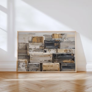 May include: Abstract art print in a wooden frame. The artwork features a textured, layered design of rectangular blocks in shades of beige, gray, black, and gold. The painting is displayed against a white wall with a shadow.