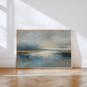 Puede incluir: Pintura abstracta de paisaje en un marco de madera clara. La obra presenta una escena serena con tonos azules, grises y beige apagados, evocando una sensación de calma. Las pinceladas crean un efecto texturizado, sugiriendo agua y cielo.
