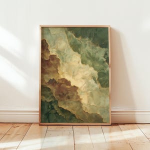 May include: Abstract art print featuring a layered design in shades of green, brown, and gold. The artwork is framed in a natural wood frame and leans against a white wall, with a wooden floor in the foreground.