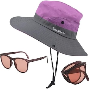 May include: A purple and gray sun hat with a black drawstring and the text "Sun Shade" on the brim. The hat is paired with a set of brown folding sunglasses.