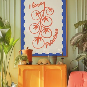 Pode incluir: Uma impressão emoldurada com fundo branco e borda azul ondulada. A impressão apresenta uma ilustração vermelha de tomates e as palavras "I love potatoes" em vermelho. A obra de arte está pendurada acima de um armário laranja.