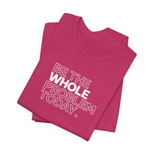 以下が含まれることがあります： 白い文字で「BE THE WHOLE PROBLEM TODAY.」とプリントされたピンクのTシャツ