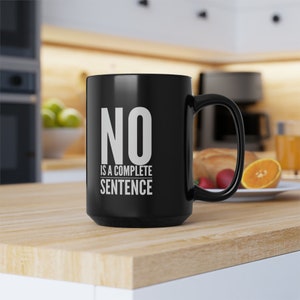 Puede incluir: Una taza de café negra con un gráfico blanco que dice "NO is a complete sentence".