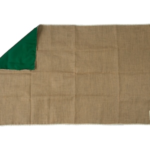 May include: A brown burlap fabric placemat with a green fabric backing and white trim. The placemat has a small white label with the text "The Burlap Company" on the bottom right corner.