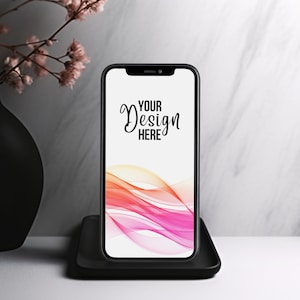 May include: A black smartphone with a white background and the text "YOUR DESIGN HERE" on the screen. The phone is sitting on a black stand.