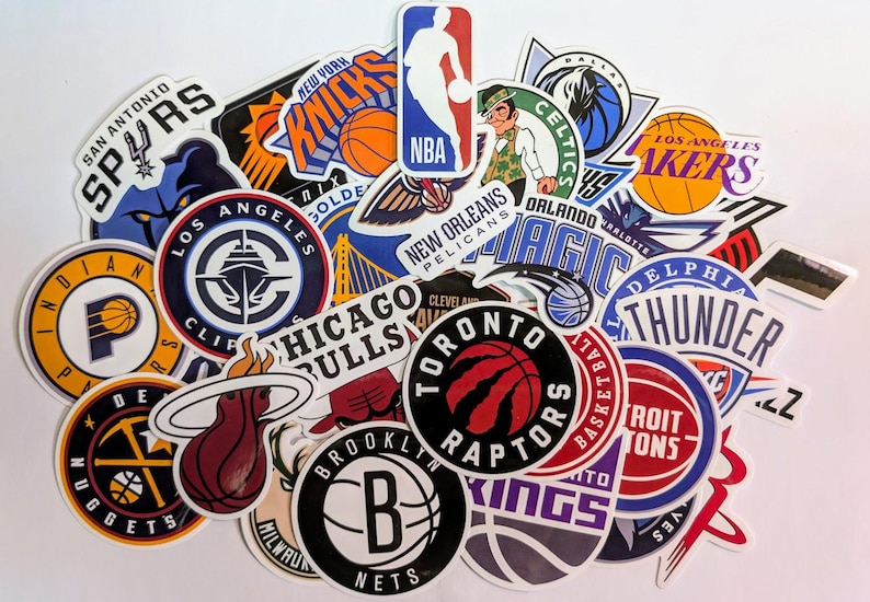 May include: A collection of colorful NBA team logo stickers. The stickers feature logos for teams such as the Celtics, Lakers, Bulls, Raptors, and more.