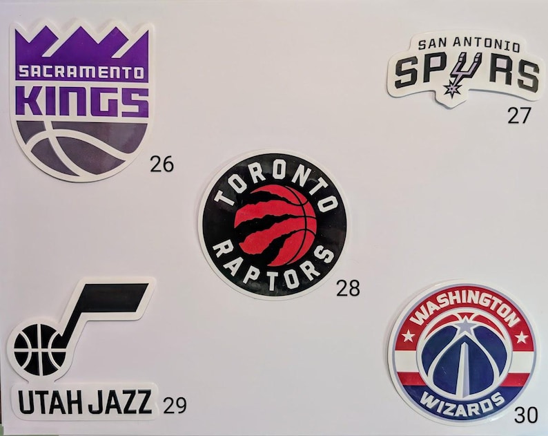 May include: A collection of ten NBA team logos, including the Sacramento Kings, San Antonio Spurs, Toronto Raptors, Utah Jazz, and Washington Wizards. Each logo is a sticker with a number underneath.