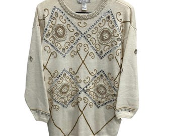 May include: A cream-colored sweater with a diamond pattern and gold and silver embellishments. The sweater has a round neckline and long sleeves.
