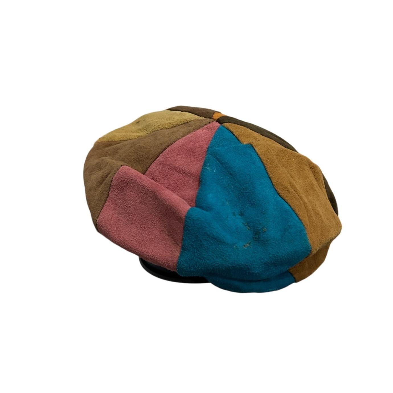 May include: A patchwork newsboy cap in a variety of colors including brown, tan, pink, and teal. The cap is made of suede or a similar material and has a rounded crown and a short brim. The cap is a unique and stylish accessory.