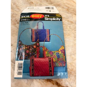 May include: A Simplicity 4729 sewing pattern envelope for bags in one size. The cover features illustrations of four different handbags: a blue quilted tote, a black floral hobo bag, a red quilted tote, and a colorful owl-print hobo bag.