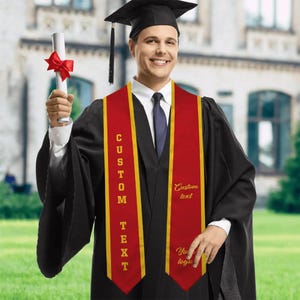 May include: A person wearing a black graduation gown and cap, holding a diploma tied with a red ribbon. The person is wearing a red and gold graduation sash with the words "CUSTOM TEXT" and "Your logo" printed on it.
