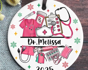 May include: A white ceramic ornament with a black ribbon for hanging. The ornament features medical-themed illustrations in pink and white, including a stethoscope, scrubs, and a prescription bottle. The name "Dr. Melissa" and the year "2025" are also displayed.