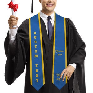 May include: A person wearing a black graduation gown with a blue and gold sash. The sash has the words "CUSTOM TEXT" vertically and "Custom text" and "Your logo" in gold script. The person is holding a diploma with a red ribbon.
