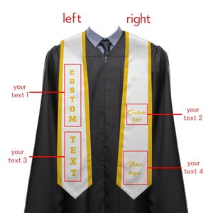 May include: A black graduation gown with a white and gold custom sash. The sash has the words "CUSTOM TEXT" printed vertically on the left side and "Custom text" and "Your logo" on the right side. The sash is draped over the gown.