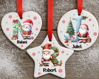 May include: Three personalized Christmas ornaments with red ribbons. One is heart-shaped, one is star-shaped, and one is round. Each features a letter, a Santa Claus illustration, and a name: Nalani, Robert, and Juliet. The ornaments have a festive holiday theme.