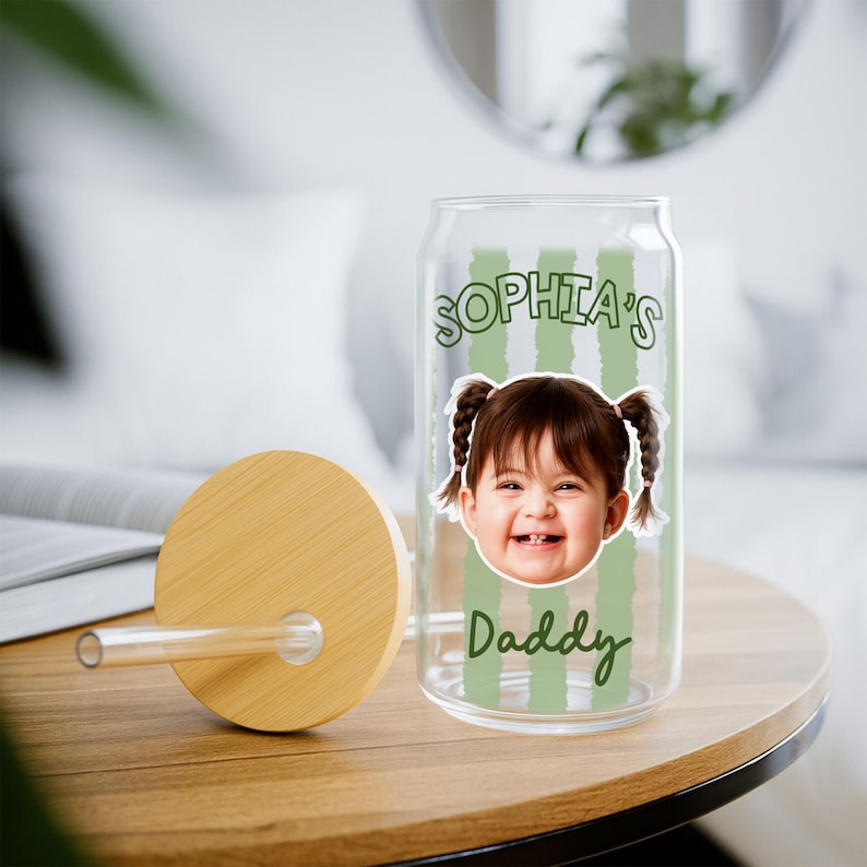 K&ouml;nnte beinhalten: Ein klares, dosenf&ouml;rmiges Glas mit Bambusdeckel und Strohhalm. Das Glas zeigt ein Foto eines l&auml;chelnden Kindes und den Text "Sophia's Daddy" in Gr&uuml;n. Gr&uuml;ne vertikale Streifen verzieren das Glas.