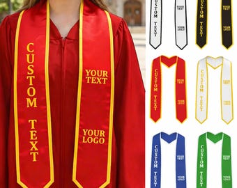 May include: A red graduation stole with yellow trim and the text "CUSTOM TEXT" in gold. The stole also features space for "YOUR TEXT" and "YOUR LOGO". Additional stoles in white, black, red, gold, blue, and green are also shown.