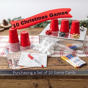 May include: A set of 10 Christmas games featuring red plastic cups, a silver box, white cotton balls, colorful markers, and game cards with the text 10 Christmas Games and Shopping List. The set includes a red marker on a card.