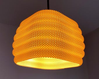 Puede incluir: Una lámpara colgante redonda y texturizada de color amarillo con un patrón de panal.