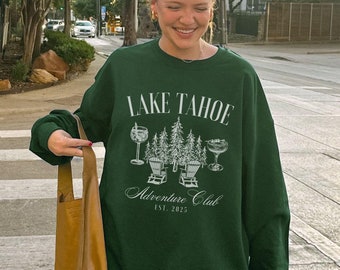 May include: A woman wearing a green sweatshirt with the text "Lake Tahoe Adventure Club Est. 2015" and a brown tote bag.