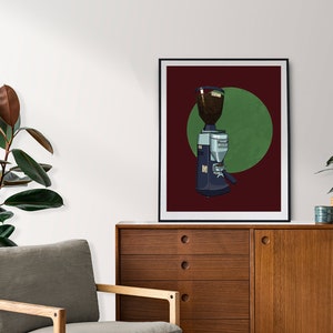 May include: A framed print featuring a coffee grinder illustration. The grinder is dark blue and silver, set against a burgundy background with a green circle. The print is displayed on a wooden cabinet.