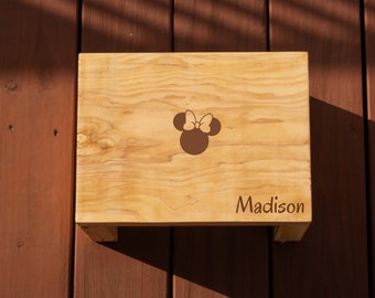 May include: A wooden step stool with a brown Minnie Mouse silhouette and the name "Madison" engraved on the top.