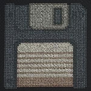 Könnte beinhalten: Ein schwarz-weißes Pixelbild einer Diskette. Die Diskette ist hellbraun mit einem schwarzen Etikett und einem schwarzen Schlitz.