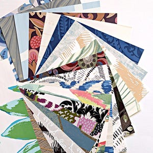 May include: A fan of various patterned wallpaper samples. The samples display a range of colors, including blue, green, pink, and brown. The patterns include floral, geometric, and abstract designs, arranged in a semi-circular shape.