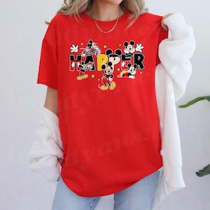 A person wearing a red t-shirt with the word "HAPPY" printed on it, along with various Disney characters.