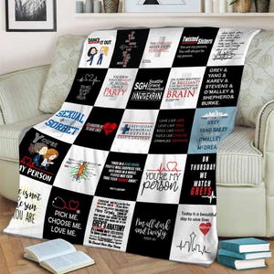 May include: A black and white throw blanket with various quotes and phrases from the TV show Grey's Anatomy. The blanket features a checkerboard design with quotes like "You're my person" and "Pick me, choose me, love me."