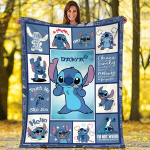 Puede incluir: Una manta azul y blanca con el personaje Stitch de Lilo & Stitch. La manta tiene un dise&ntilde;o de patchwork con varias im&aacute;genes de Stitch, junto con las frases "Ohana significa familia" y "No soy raro". Tambi&eacute;n aparece el nombre "Danya".