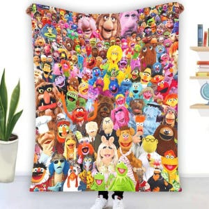 May include: A colorful blanket featuring a collage of Muppet characters. The blanket showcases a variety of beloved puppets in a vibrant and detailed arrangement. The design includes characters like Kermit, Miss Piggy, and many more.